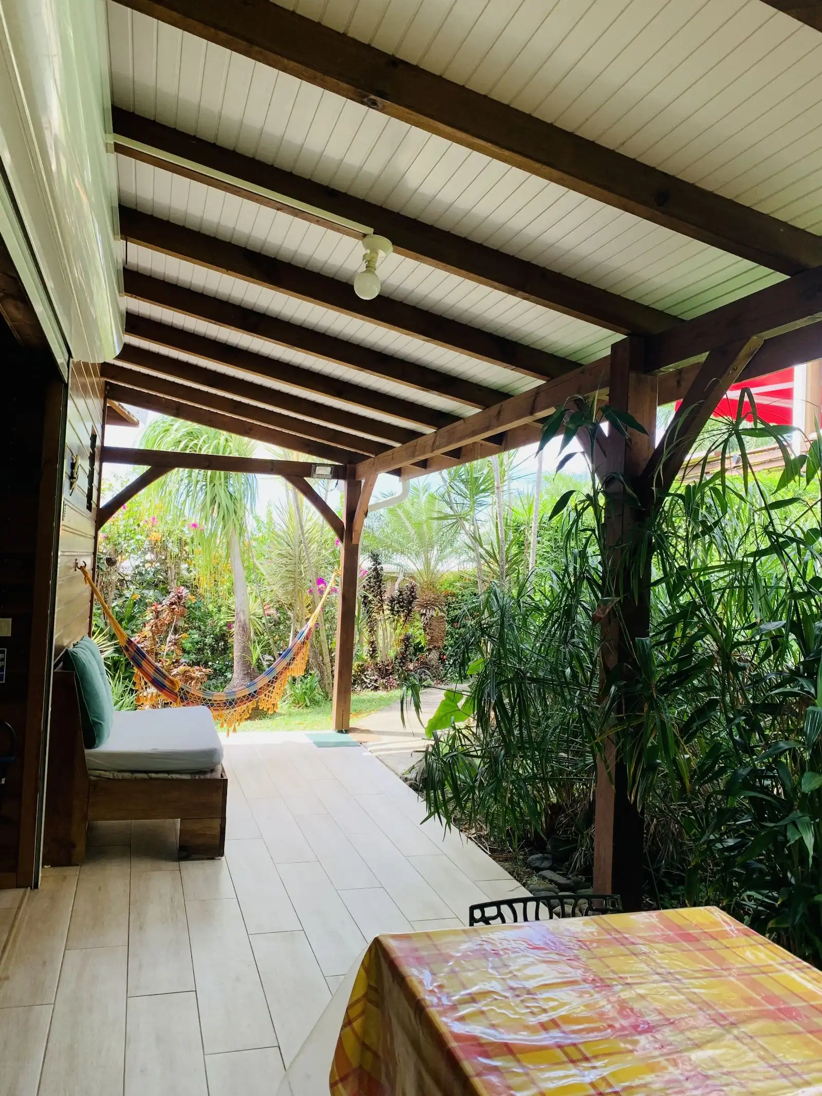 La terrasse dans la longueur, avec sa banquette, son hamac et la végétation autour